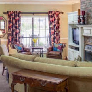 A cozy living room with a large sofa, colorful curtains, and a fireplace.