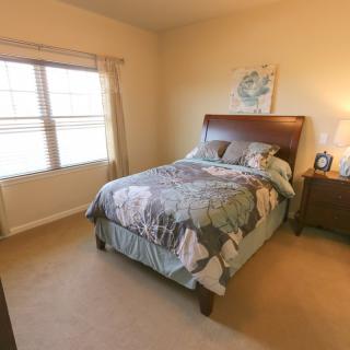 A cozy bedroom with a neatly made bed and natural light from the window.