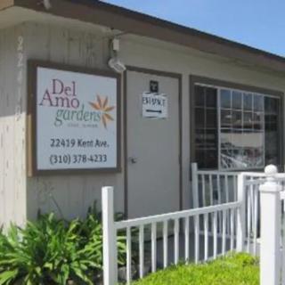 Exterior view of the Del Amo Gardens office building with signage and a white fence.