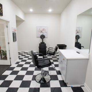 A tidy barbershop with a checkered floor and modern furnishings.