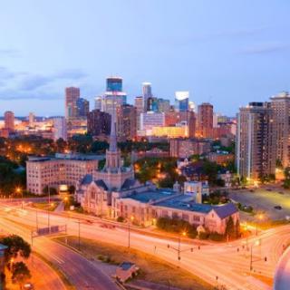 A vibrant evening skyline of downtown Minneapolis, showcasing a blend of historical and modern architecture.
