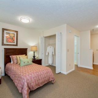 A cozy bedroom with a single bed, artwork on the wall, and an open closet.