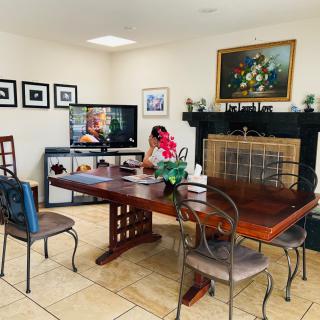 A cozy dining room with a wooden table, chairs, and a fireplace, featuring a TV and various decor elements.