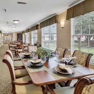 An elegantly set dining area with multiple tables and chairs, featuring large windows that allow natural light to fill the space.