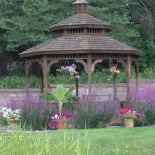 A picturesque garden gazebo surrounded by vibrant flowers and lush greenery.