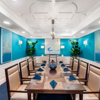 A sophisticated dining room with a modern design featuring a large conference table, elegant seating, and vibrant blue walls.