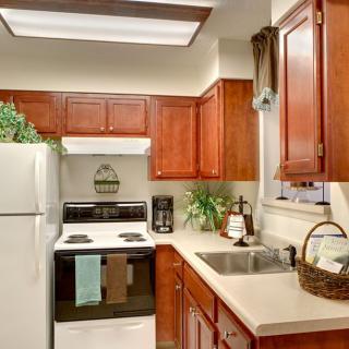 A cozy kitchen with wooden cabinets, a stove, and a refrigerator.