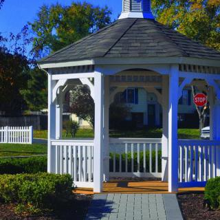 A charming white gazebo stands in a landscaped garden.