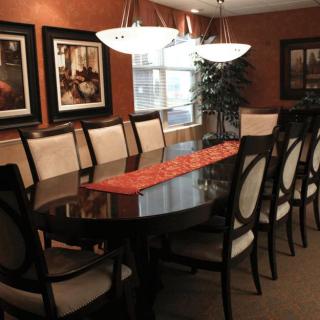 A modern dining room with a large table and elegant chairs, complemented by artwork and ambient lighting.