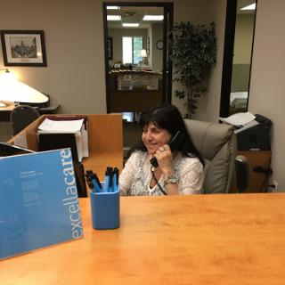 A receptionist answers a phone call at an office desk.