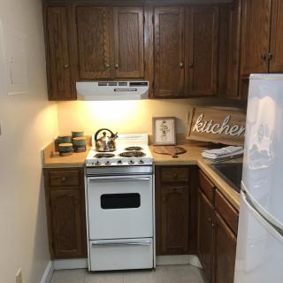 A cozy kitchen with wooden cabinets, a stove, and a refrigerator.