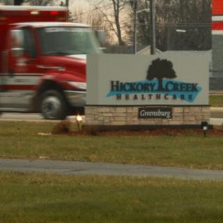 An emergency vehicle passes by the Hexwood Creek Healthcare sign, indicating a facility dedicated to health services.