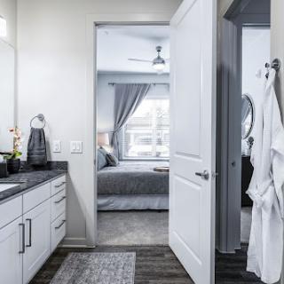 A modern bathroom with a view of a stylish bedroom, showcasing clean lines and neutral tones.