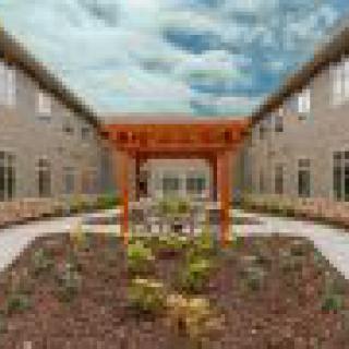 A beautifully landscaped courtyard with a wooden arbor and modern buildings on either side.