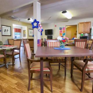 A cozy dining area with tables and chairs, featuring decorative elements and a wooden floor.