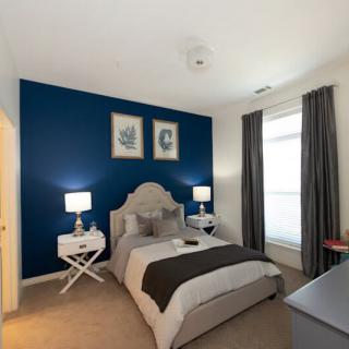 A stylish bedroom with a blue accent wall, featuring a queen-sized bed flanked by nightstands and lamps.