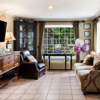 A cozy living room with a sofa, armchair, and a large window offering a garden view.