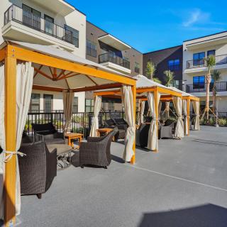 A sunny outdoor patio with cabanas and comfortable seating.