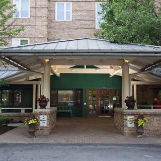 The entrance of a hotel with a covered walkway and surrounding greenery.