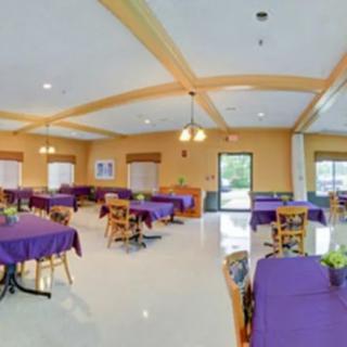 A spacious dining area with tables covered in purple tablecloths and neatly arranged chairs.