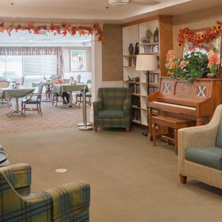 A cozy lounge area featuring a piano, seating arrangements, and festive decorations.