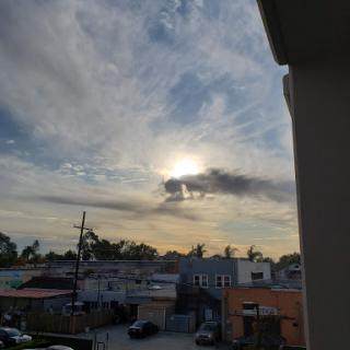 A beautiful evening sky with clouds and the sun setting over an urban landscape.