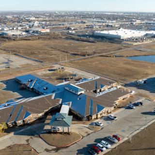 An aerial view of a school complex surrounded by open land and urban development.