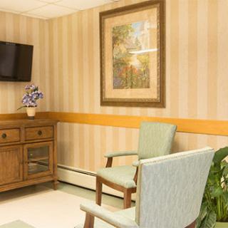 A cozy waiting room featuring comfortable chairs, a television, and decorative elements.
