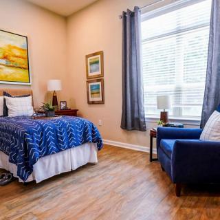 A cozy bedroom with a bed and chair, featuring soft lighting and tasteful decor.