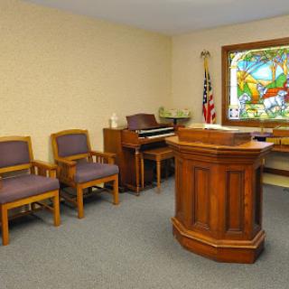 A view of a small courtroom featuring wooden furniture and a colorful stained glass window.
