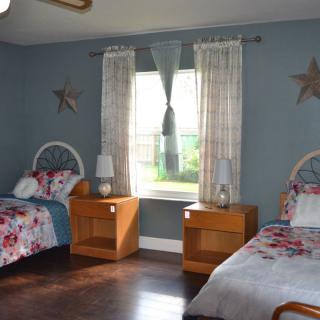 A cozy bedroom with twin beds and blue walls, featuring wooden furniture and decorative elements.