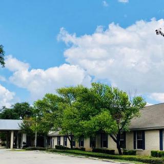 A row of buildings with trees and a cloudy blue sky in the background.