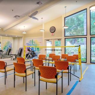 An indoor exercise room with gym equipment and a seating area.