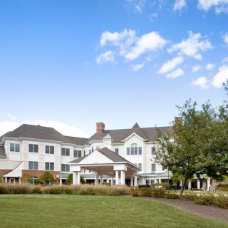 A large residential building with a landscaped front yard under a clear blue sky.