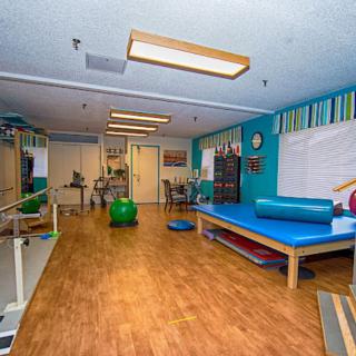 A well-equipped physical therapy room featuring exercise equipment and treatment tables.
