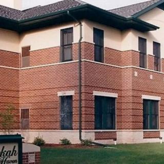 A two-story brick building with multiple windows and a tiled roof.