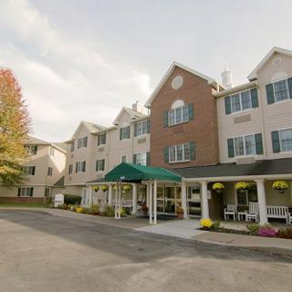 A multi-story residential building with an entrance canopy and surrounding greenery.