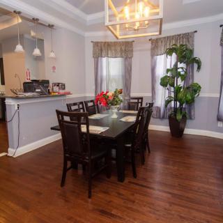 A modern dining room with a wooden table, chairs, and elegant lighting.