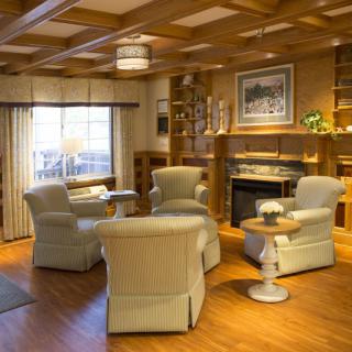 A cozy living room with armchairs arranged around a fireplace, featuring wooden floors and elegant interior design.