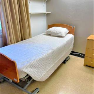 A clean and simple hospital bed in a patient room, ready for use.