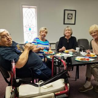 A group of four elderly individuals enjoying a meal together in a cozy setting.