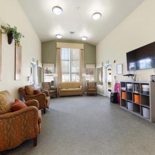 A cozy living room with comfortable seating, a television, and shelves.