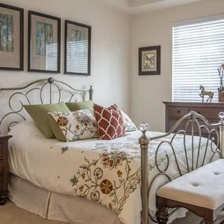 A cozy bedroom with a wrought iron bed, decorative pillows, and framed artwork on the walls.