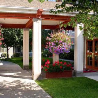 A beautifully landscaped entrance with hanging flower baskets and neatly trimmed grass.