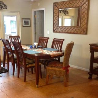 A dining room with a wooden table and chairs, complemented by a large wall mirror.