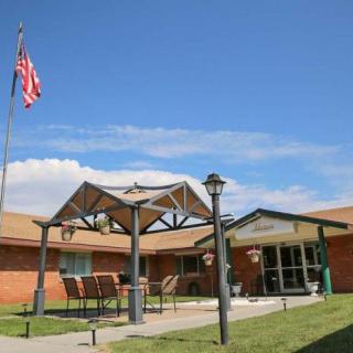 An outdoor view of a building entrance with an American flag and patio seating area.