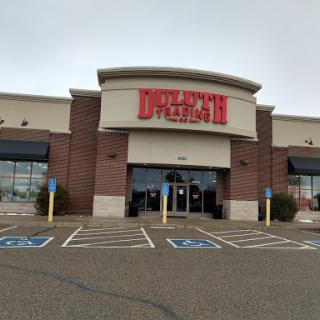 A retail store entrance viewed from the parking lot on a cloudy day.