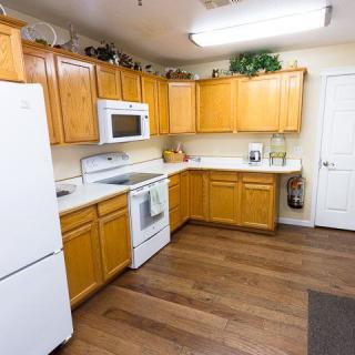 A modern kitchen with wooden cabinets and white appliances, featuring a microwave, oven, and refrigerator.
