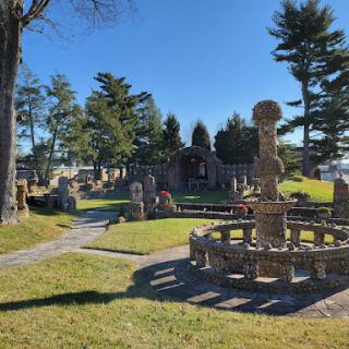 A serene view of a well-maintained cemetery, featuring ornate memorials and lush greenery.