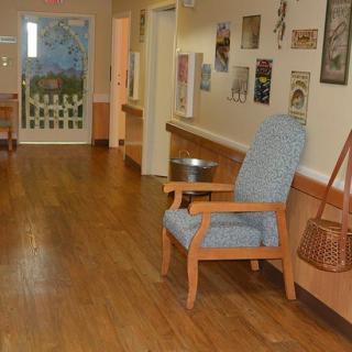 A quiet hallway featuring a wooden chair and various wall decorations.